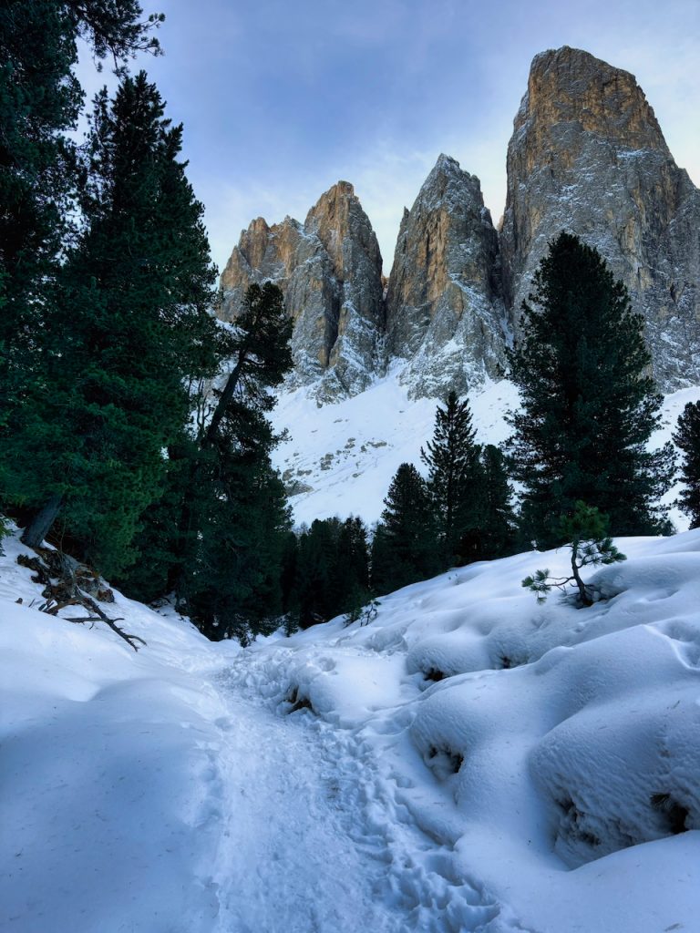 Un sentiero nella neve, sulla sfondo torri dolomitiche si ergono maestose.